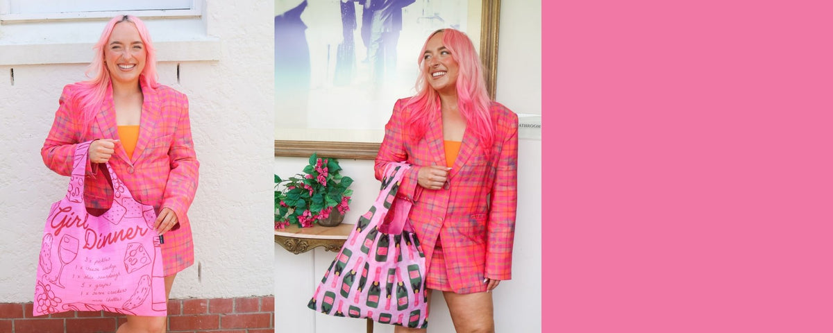 A split-screen lifestyle image showing a woman with pink hair wearing a pink plaid blazer and holding a pink shopping bag with 'Girl Dinner' written on it. The left side shows her outdoors against a white wall, and the right side shows her indoors against a framed picture, with a large solid pink block on the right side of the image.