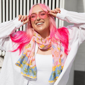 Model smiling in pink sunglasses wearing the Sunday Picnic Modal Long Scarf by Cass Deller around her neck