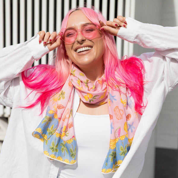 Model smiling in pink sunglasses wearing the Sunday Picnic Modal Long Scarf by Cass Deller around her neck