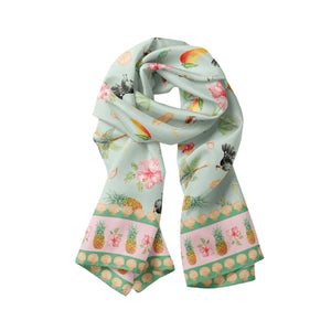 Noosa Parade Modal Long Scarf by Cass Deller, a mint green scarf with a tropical print and pink border, loosely draped