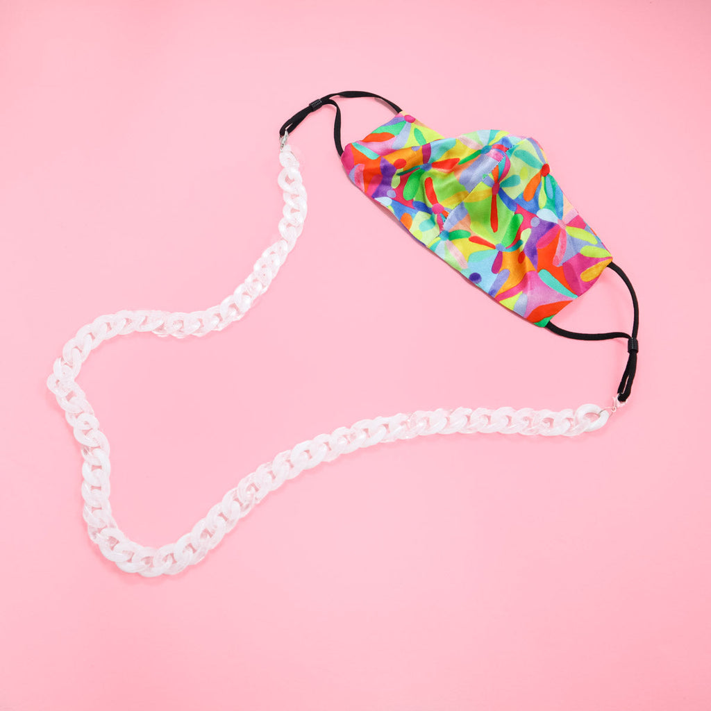 Frosted glass chain flat lay with vibrant neon face mask. 